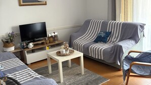 A living room with a sofa, a TV, a small table, and a fan. - Estartit Costa Brava. En bord de MER. Bel appartement avec vue sur la mer (L’Estartit (or Estartit))