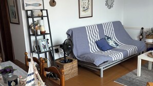 A cozy living room with a sofa, a small table, a bookshelf, and a decorative sailboat model. - Estartit Costa Brava. En bord de MER. Bel appartement avec vue sur la mer (L’Estartit (or Estartit))