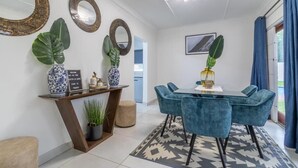 A modern dining area with a round table, blue chairs, and decorative mirrors. - Greencroft Villa (Kempton Park)