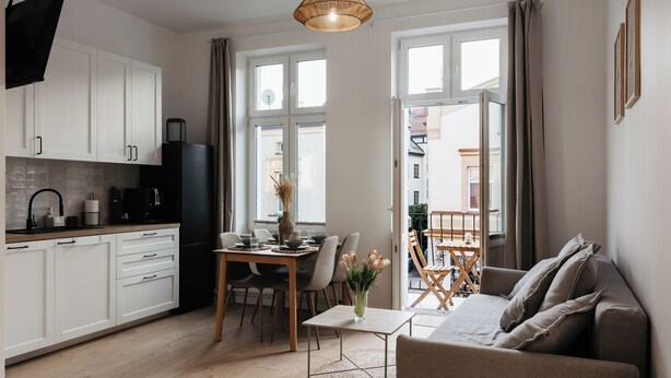 Une cuisine moderne avec des meubles blancs, un réfrigérateur noir et un coin repas comprenant une table et des chaises.