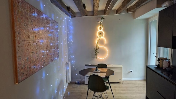 A room with exposed brick walls, a table with chairs, a radiator, and a ceiling with exposed beams. - Piccola Perla sul canale (Venezia)
