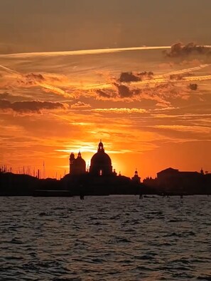 Silhouette einer Skyline mit markanten, kuppelbekrönten Gebäuden vor einem Sonnenuntergangshimmel.