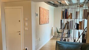 A living room with a sofa, a painting, and a shoe rack. - Piccola Perla sul canale (Venezia)