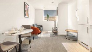 Et moderne værelse med spisebord, stole, en sofa, et lille rundt bord og et skab.
