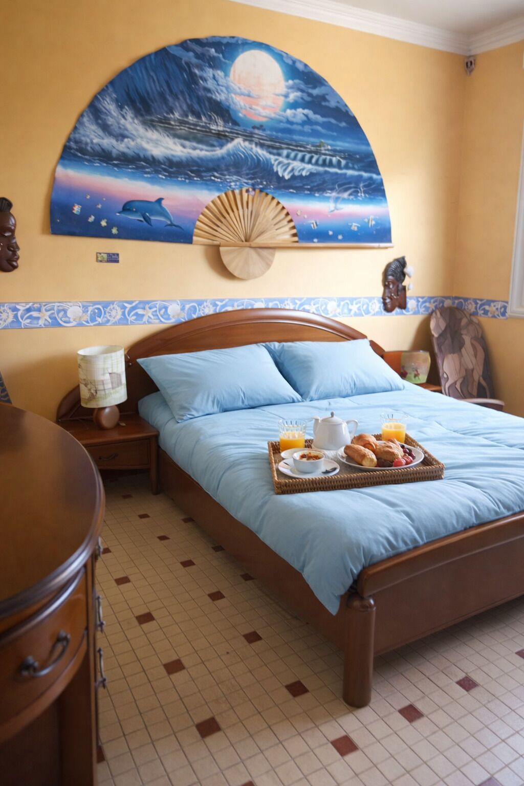 Ein Schlafzimmer mit Bett, Nachttisch, Wandventilator und Wandbild.