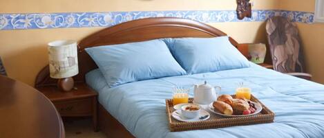 Ein Schlafzimmer mit Bett, Nachttisch, Wandventilator und Wandbild.