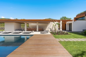 A modern outdoor pool area with a wooden deck, lounge chairs, and a pergola. - Luxury villa with pool, Etna view - Fiumè, Di Casa In Sicilia (Fiumefreddo di Sicilia)