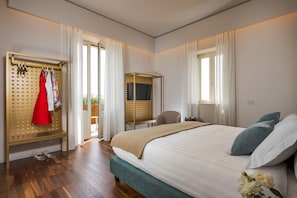 Une chambre d’hôtel moderne avec un grand lit, une armoire avec des vêtements suspendus, un bureau et une chaise.