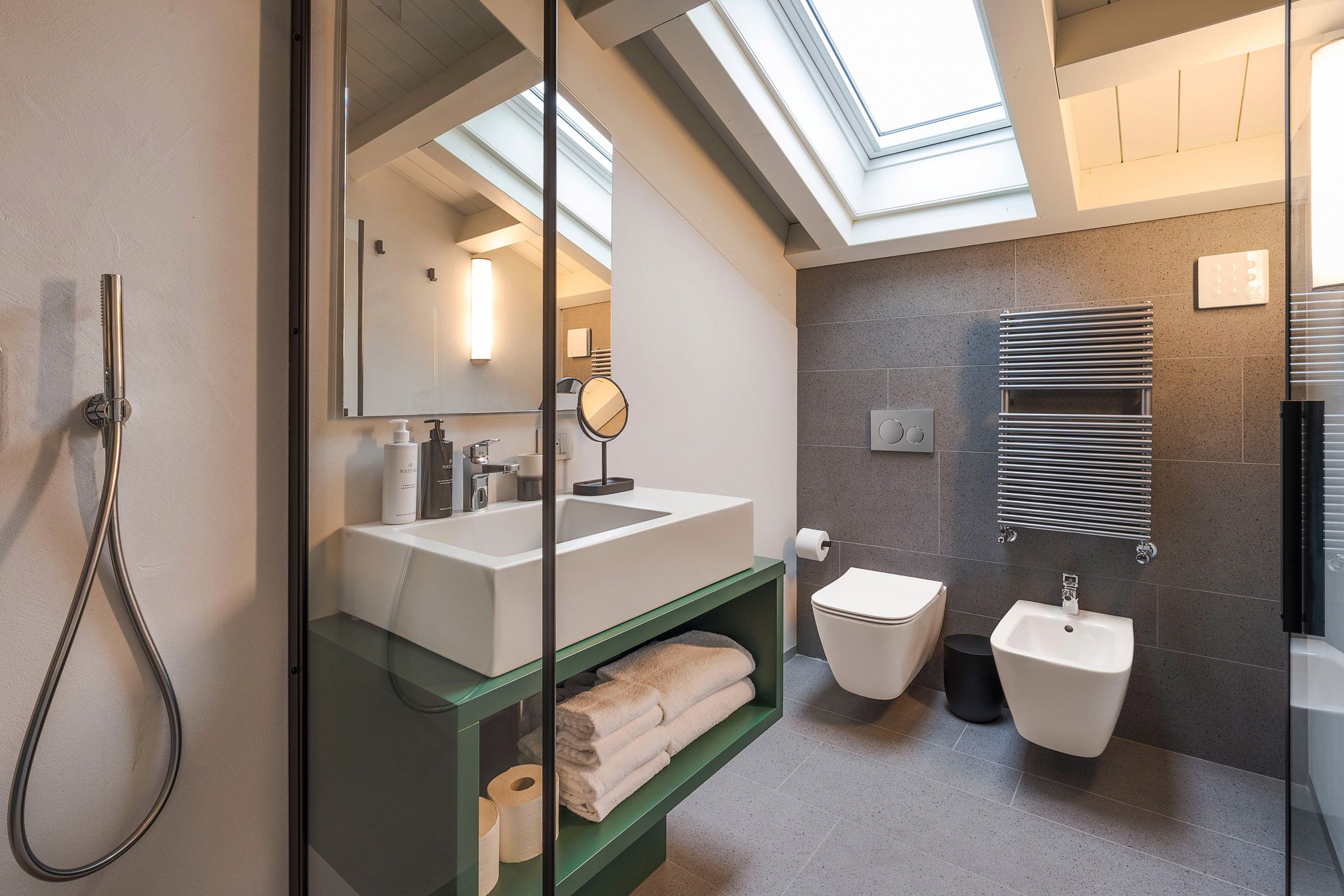 Ein modernes Badezimmer mit Oberlicht, Dusche, Waschbecken, Toilette und Bidet.