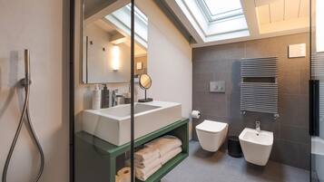 Ein modernes Badezimmer mit Oberlicht, Dusche, Waschbecken, Toilette und Bidet.