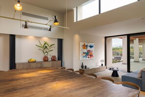 A modern dining area with a large wooden table, chairs, and a view of the outdoors through a glass door. - Luxury villa with pool, Etna view - Fiumè, Di Casa In Sicilia (Fiumefreddo di Sicilia)
