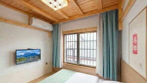 A room with a bed, a mounted TV, a window with curtains, and an air conditioning unit. - Just wait for you- English reception-Ticket reservation (Zhangjiajie)