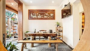 A rustic interior with a wooden table, a framed artwork, and a bookshelf. - Just wait for you- English reception-Ticket reservation (Zhangjiajie)
