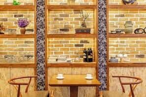 A brick wall with shelves displaying various items, a wooden table with two chairs, and a patterned wallpaper section. - Just wait for you- English reception-Ticket reservation (Zhangjiajie)