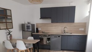 Una cocina moderna con armarios oscuros, encimera de madera, horno empotrado y lavavajillas.
