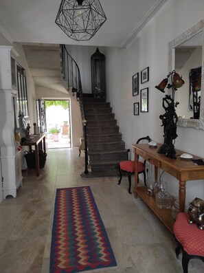 A staircase leading to an upper floor, a wooden console table with decorative items, a patterned rug, and a large mirror. - Maison de charme au calme, 15mn de Nimes et de son passé historique. (Milhaud)