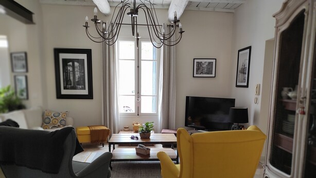 Ein Wohnzimmer mit Fernseher, zwei Sesseln, einem Couchtisch und einer Kandelaber.