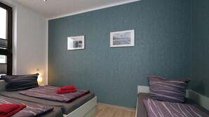 A room with two beds, a window, and two framed pictures on the wall. - Appartement Nr. 08 (Rostock)