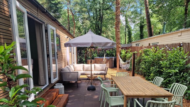 A patio with a wooden table and chairs, a sofa, and a hammock.