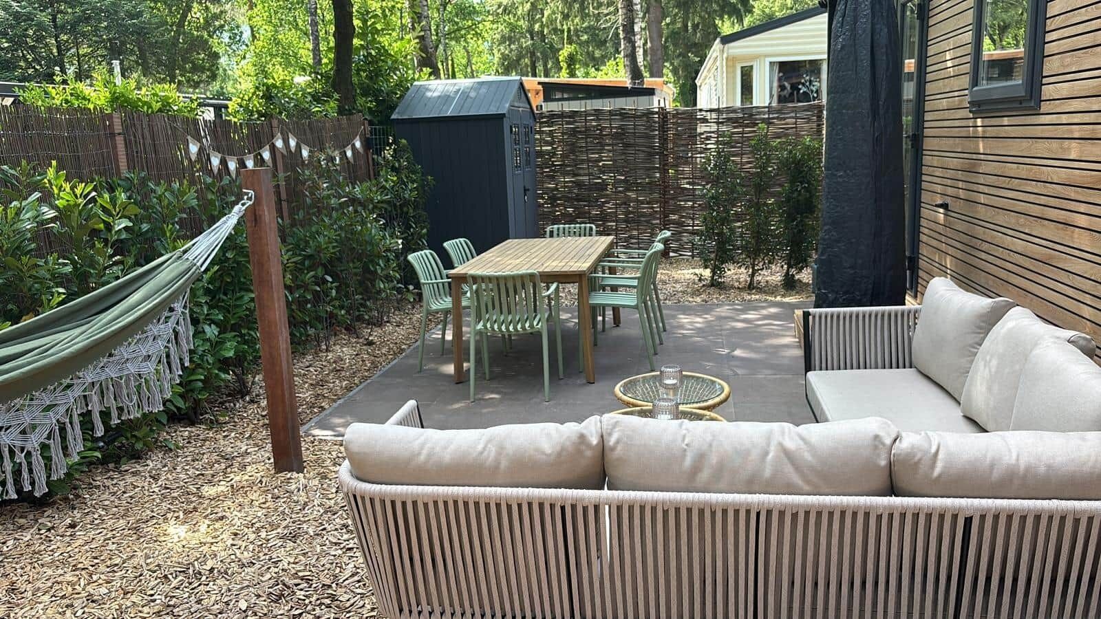 A patio with a sofa, chairs, a table, and a hammock.