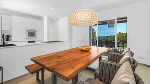 A modern kitchen with white cabinetry, a wooden dining table, and a large pendant light. - Exklusiv Sea View Villa with Pool in Paguera Mallorca Southwest (Peguera)
