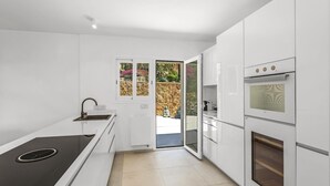 A modern kitchen with white cabinetry, a built-in stove, and an oven. - Exklusiv Sea View Villa with Pool in Paguera Mallorca Southwest (Peguera)
