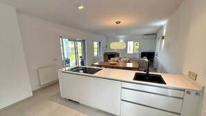 A modern kitchen with a central island, built-in appliances, and a dining area with a sofa. - Exklusiv Sea View Villa with Pool in Paguera Mallorca Southwest (Peguera)