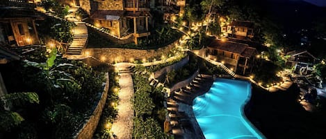 Un resort con varias edificaciones, una piscina y un camino de piedra.