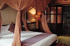 A four-poster bed with a canopy, a bedside table with a lamp, and a wicker storage unit. - JARDIN de PULUONG RESORT & SPA (Pu Luong)