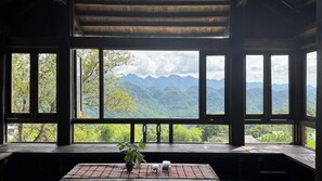 Une pièce dotée de grandes fenêtres donnant sur un paysage de montagnes et de forêts.
