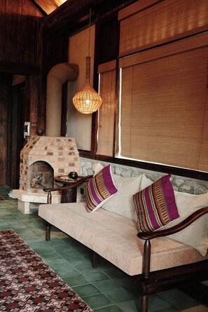 A cozy room with a built-in fireplace, a cushioned bench, and a woven light fixture. - JARDIN de PULUONG RESORT & SPA (Pu Luong)