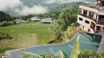 Un resort con piscina, terrazas de arrozales y montañas al fondo.