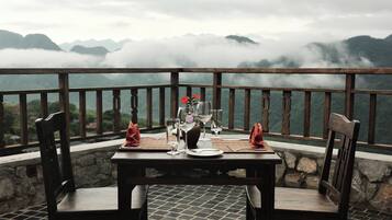 A table set for two with a view of mountains and clouds.