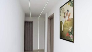 Um corredor com luminária moderna, uma porta e um pôster emoldurado na parede.