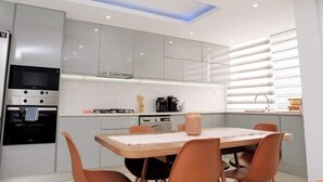 Uma cozinha moderna com área de refeições, eletrodomésticos embutidos e uma janela com persianas.