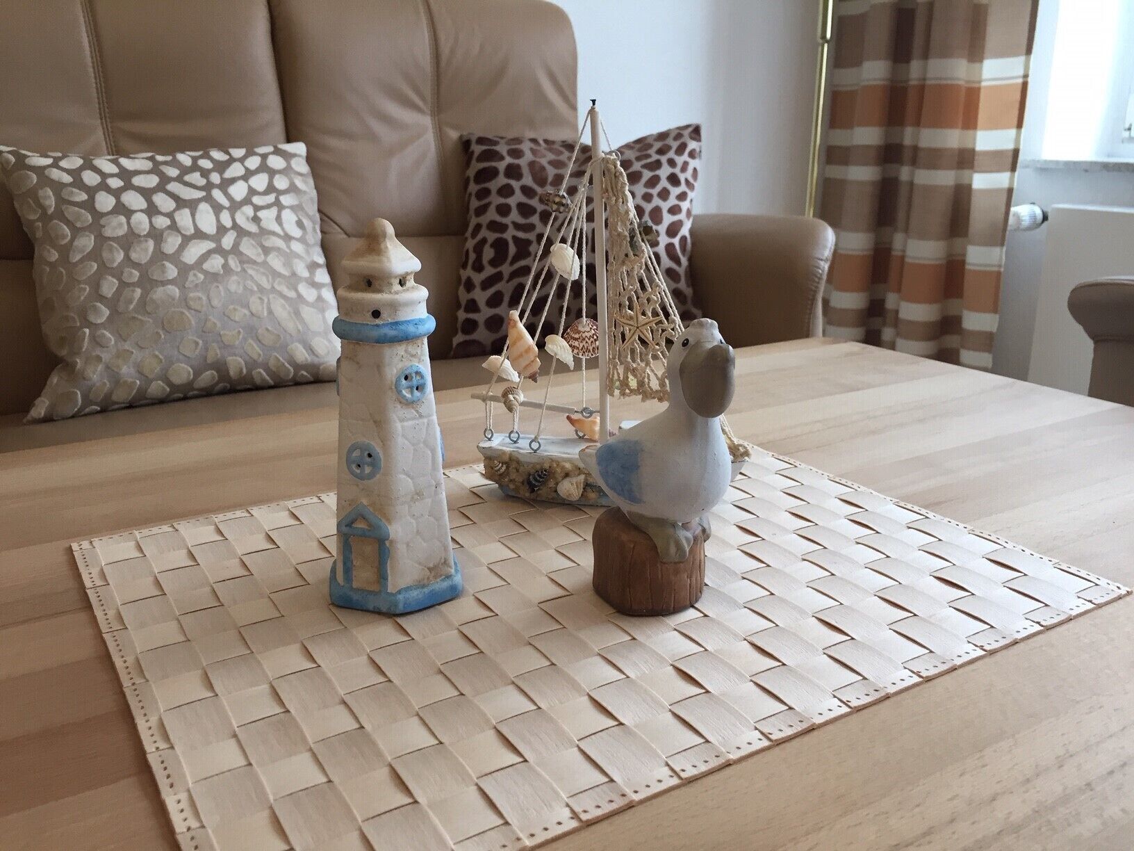 A room with a woven placemat, a decorative lighthouse, and a bird figurine on a table.