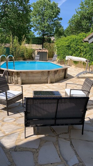 Ein Pool mit Holzterrasse, Liegestühlen und einer Steinterrasse.