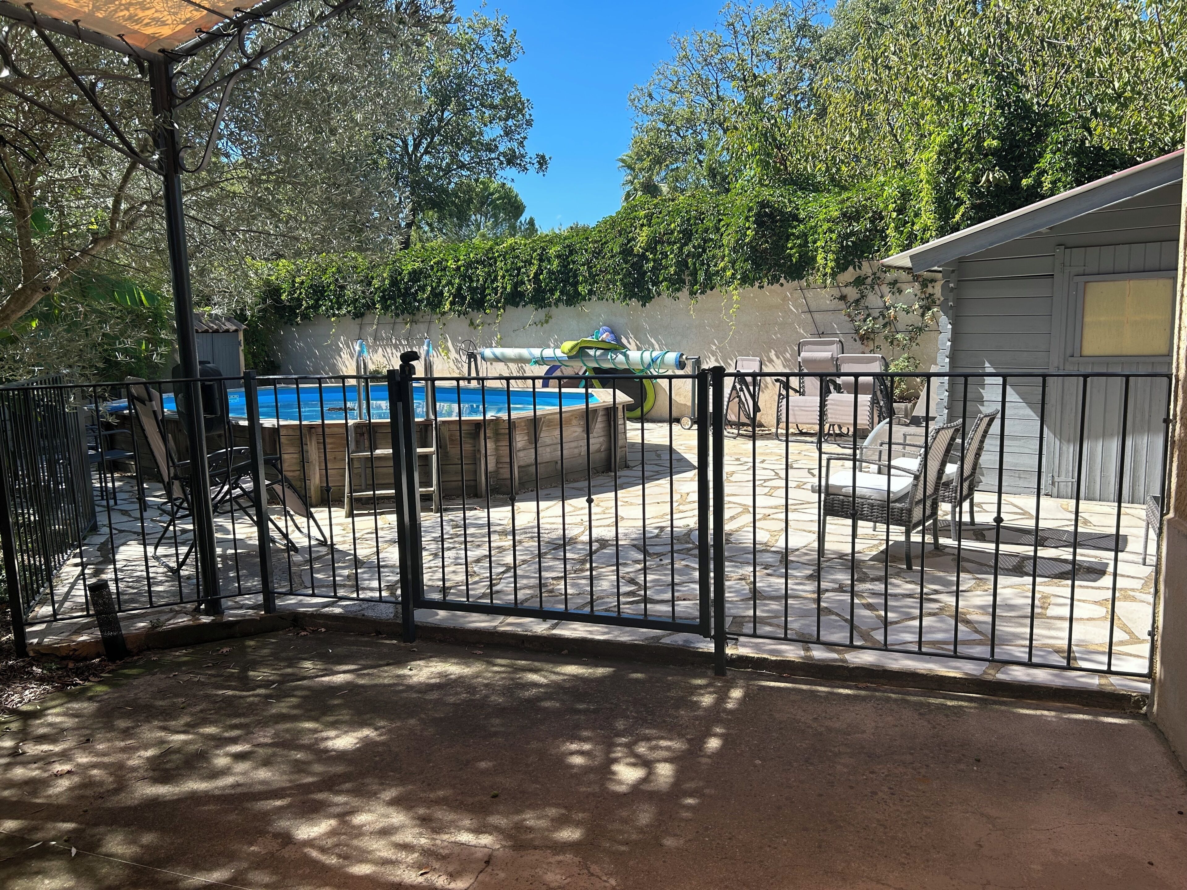 A backyard with a swimming pool, patio furniture, and a fenced area.
