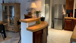Une cuisine moderne avec un îlot central en bois, une cuisinière encastrée et un réfrigérateur.