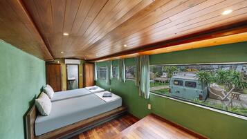 Una habitación con una cama, una ventana con vista a una camioneta y una pared verde.