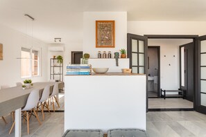 Une cuisine moderne dotée d’un îlot central, d’un coin repas avec des chaises et d’une vue sur la salle de bain adjacente.