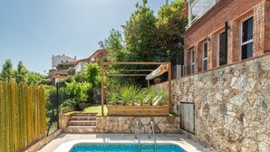 Une piscine avec un mur en pierre et une terrasse en bois.