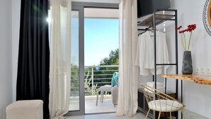 A modern room with a balcony, a TV mounted on the wall, a wooden table, a chair, and a small stool. - SunDay Free Airport Shuttle (Spata-Artemida)