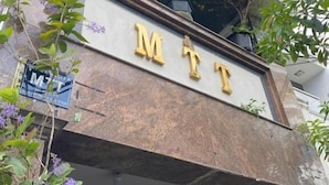 A building with the letters 'MTT' prominently displayed on the facade, surrounded by greenery and potted plants. - Hotel Airport MTT (Ho Chi Minh City)