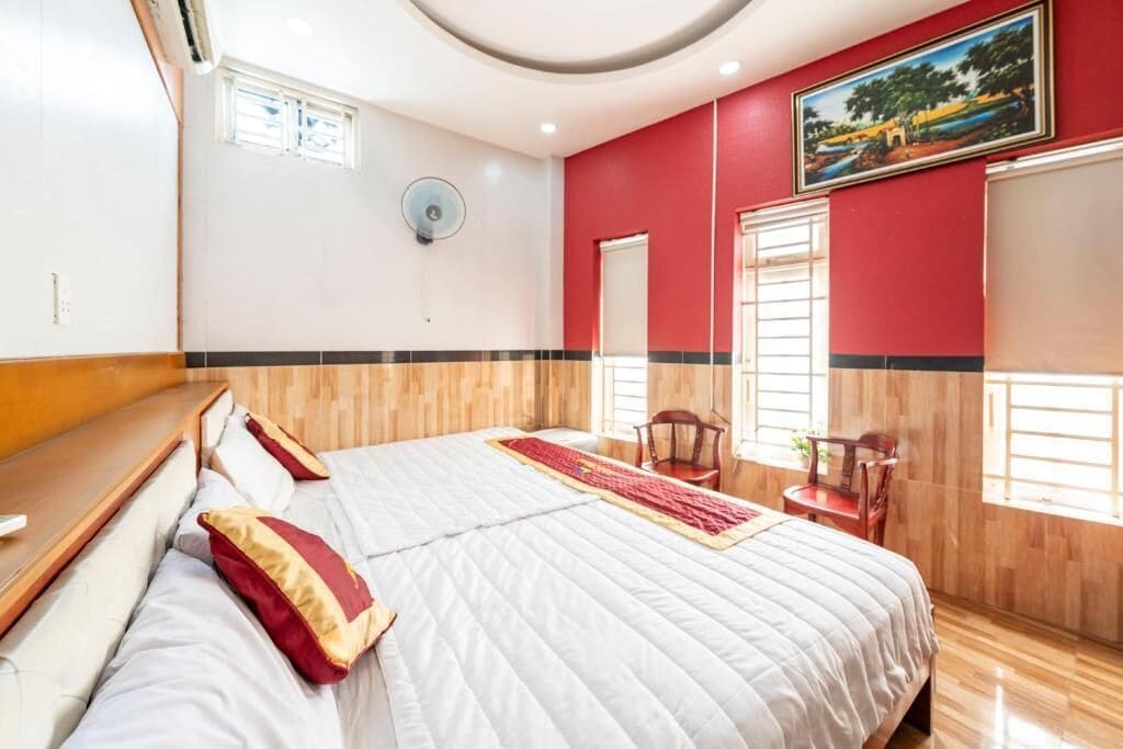 Een slaapkamer met een bed, een stoel, een raam en een schilderij aan de muur.