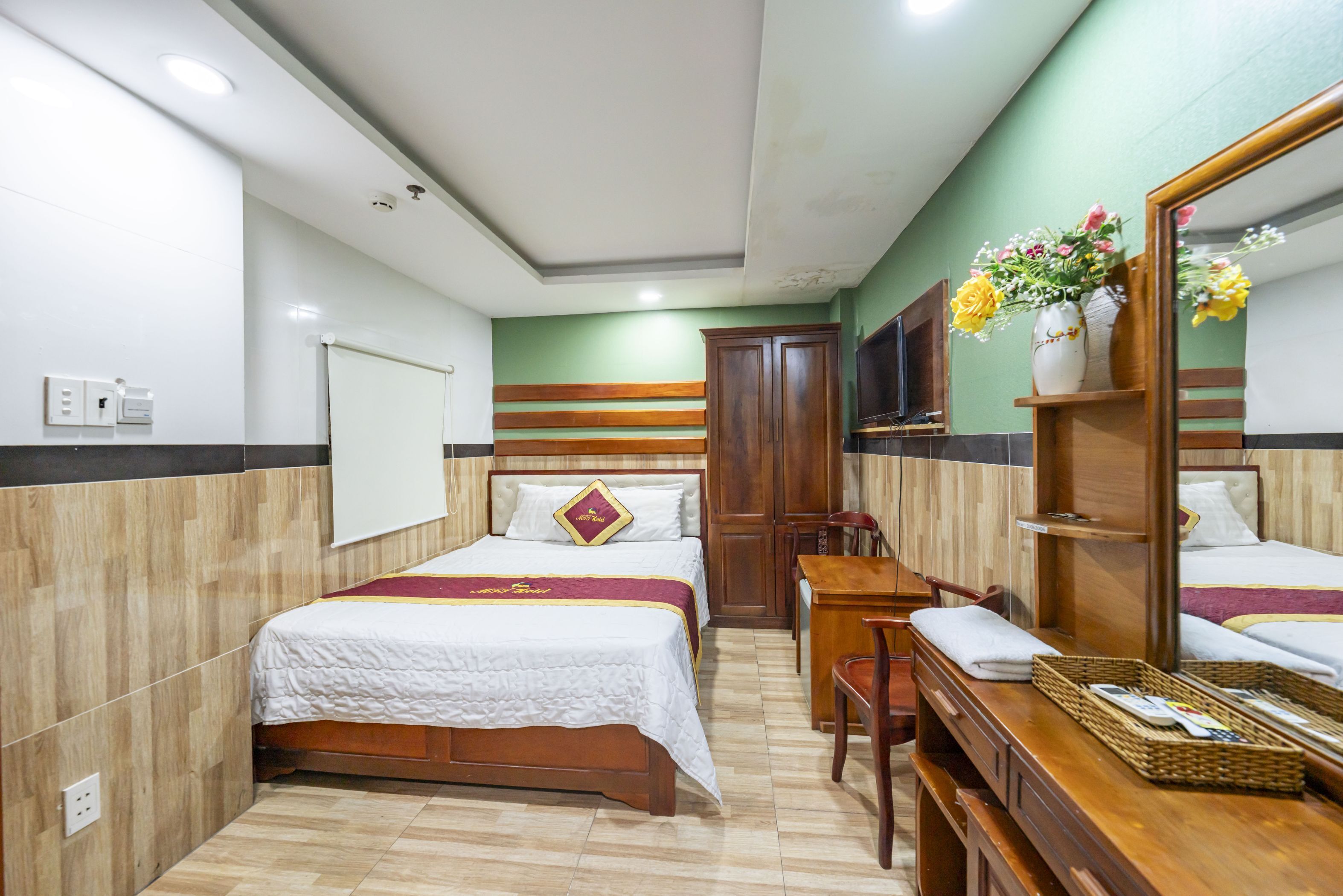 Una camera d'albergo con un letto, una scrivania, una sedia e uno specchio.