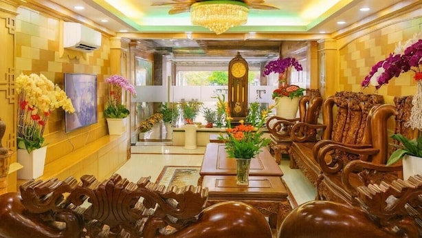 A lobby with a chandelier, wooden furniture, and potted plants. - Hotel Airport MTT (Ho Chi Minh City)