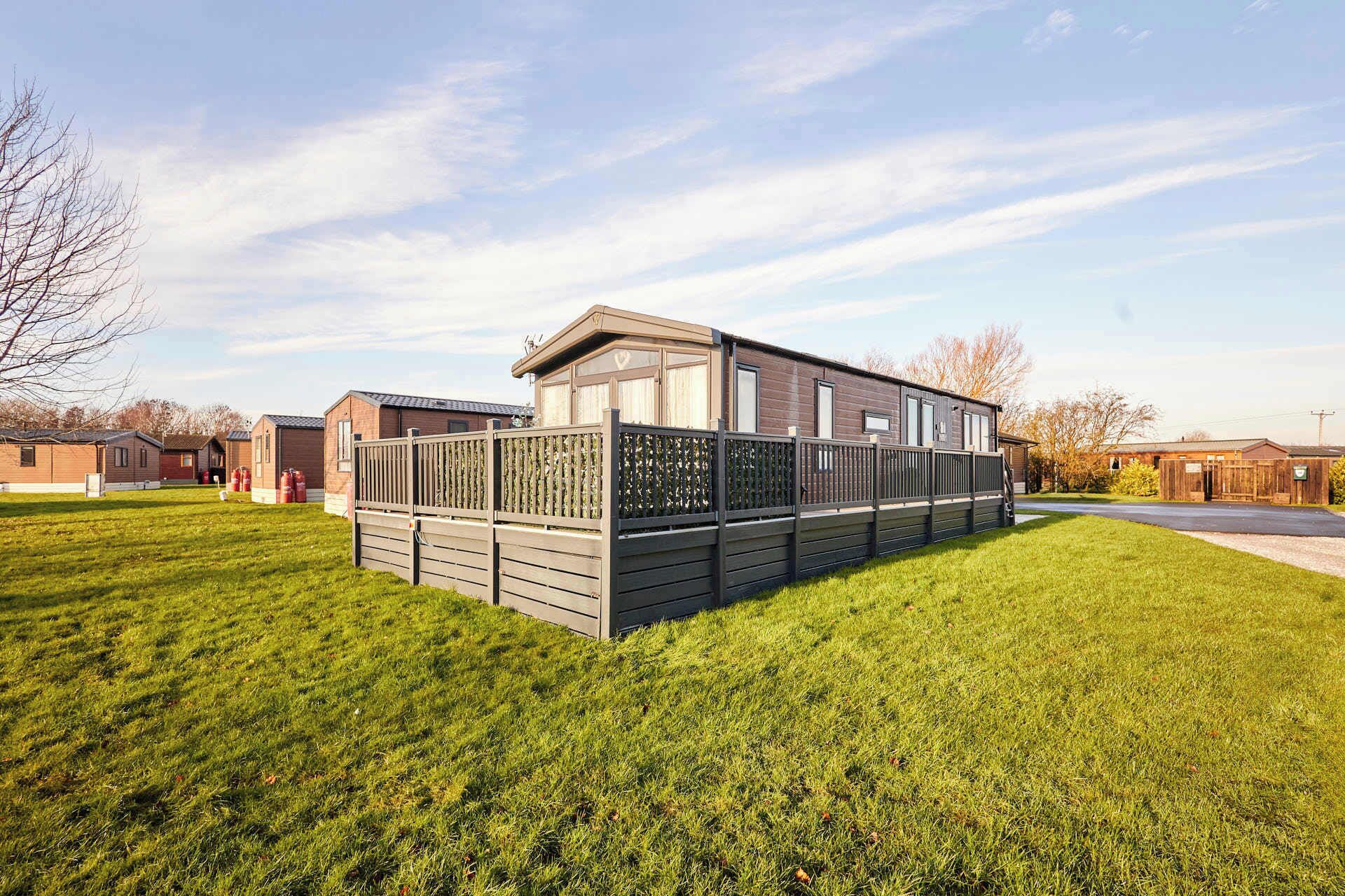 A mobile home with a fenced yard, adjacent to other similar structures.