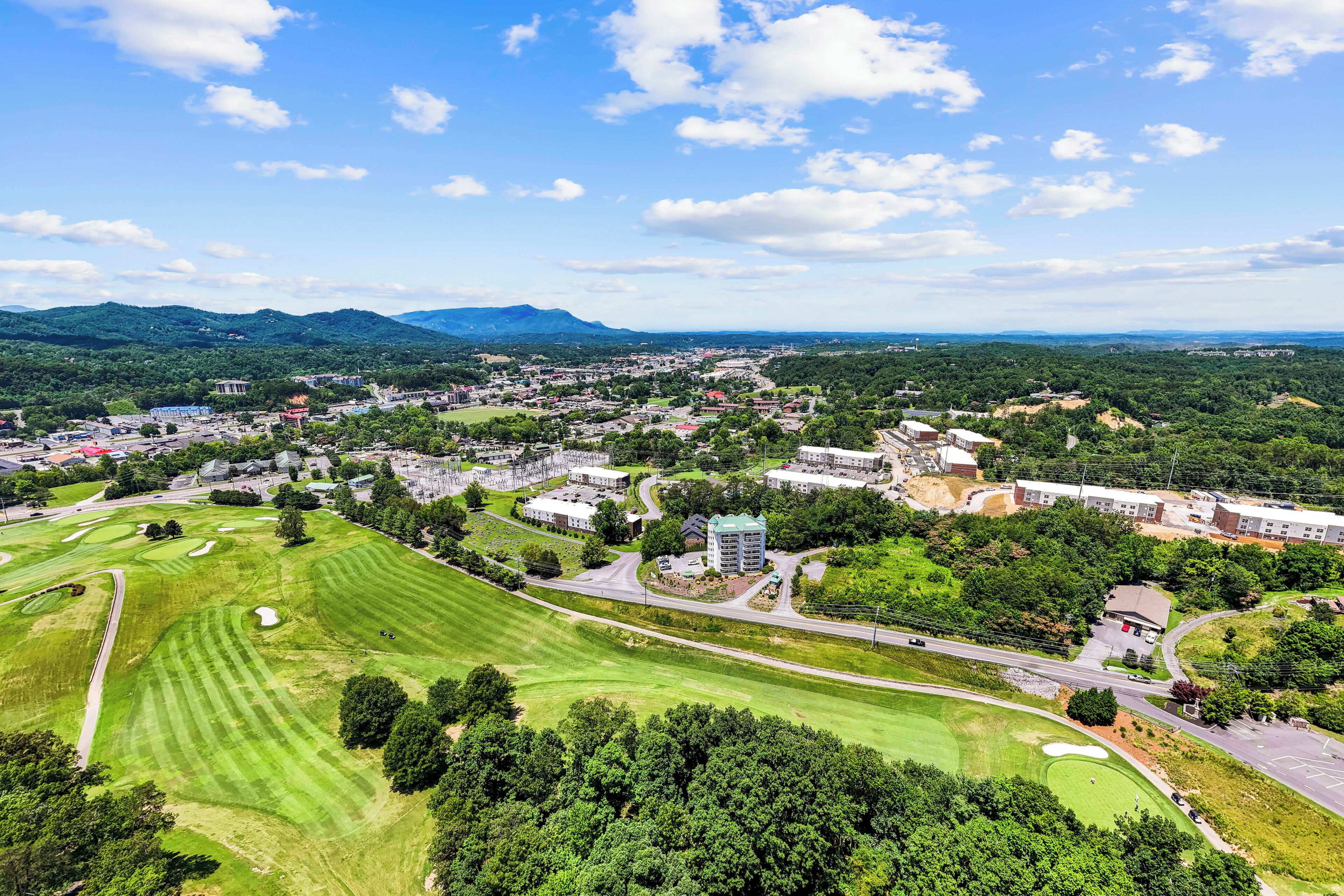 Un campo de golf con vistas a un pueblo y montañas al fondo.
