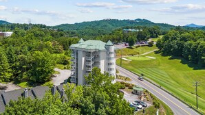 Un hôtel à plusieurs étages, doté d’une tour centrale, entouré d’une végétation luxuriante et d’un parcours de golf.